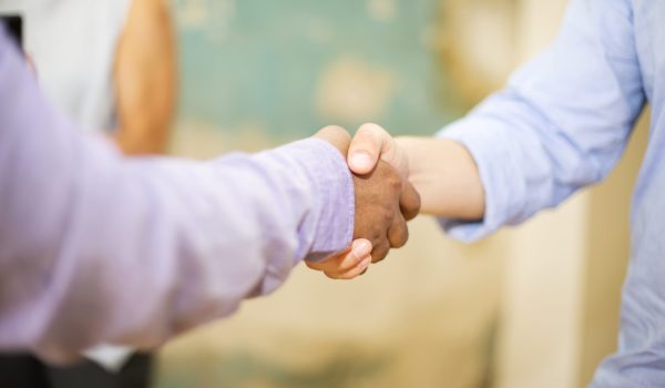 Closeup image of business partners making handshake in grunge office
